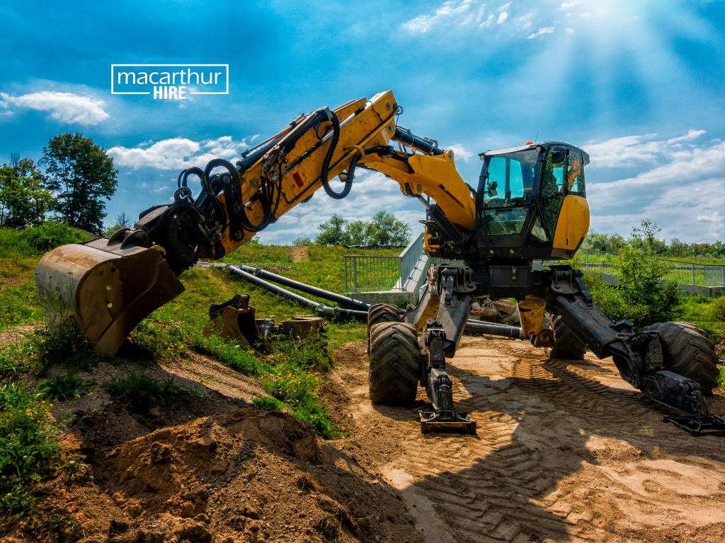 Compact excavator moving through a narrow side access path beside a residential house