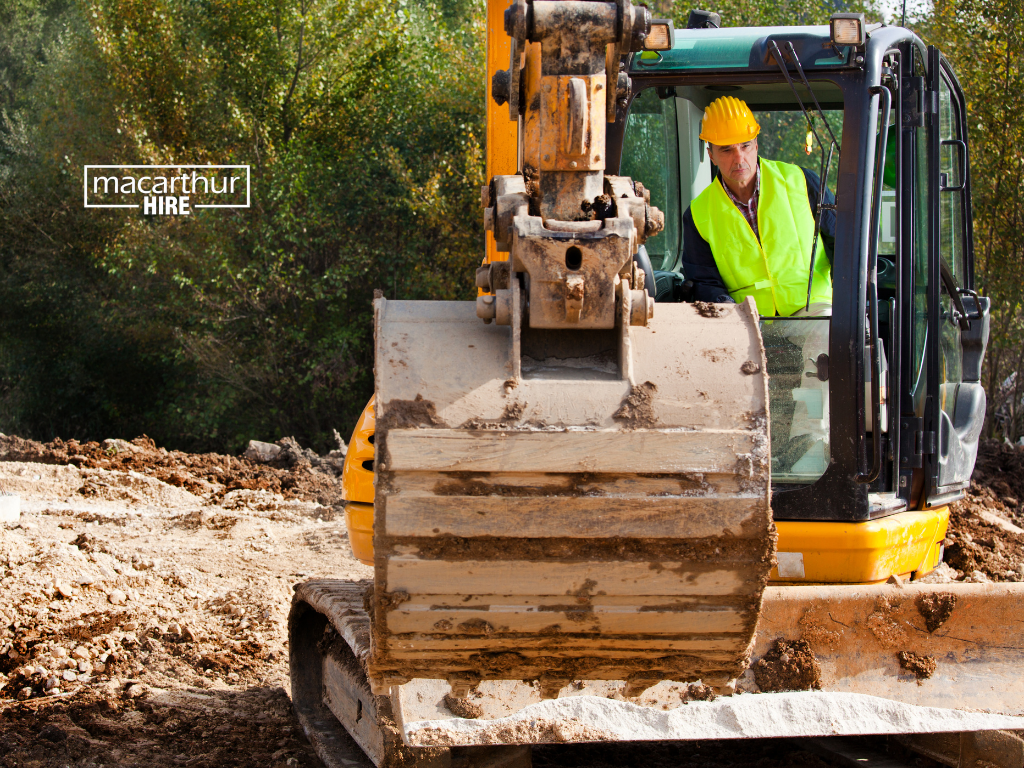 Excavator digging a trench for drainage work in a residential backyard