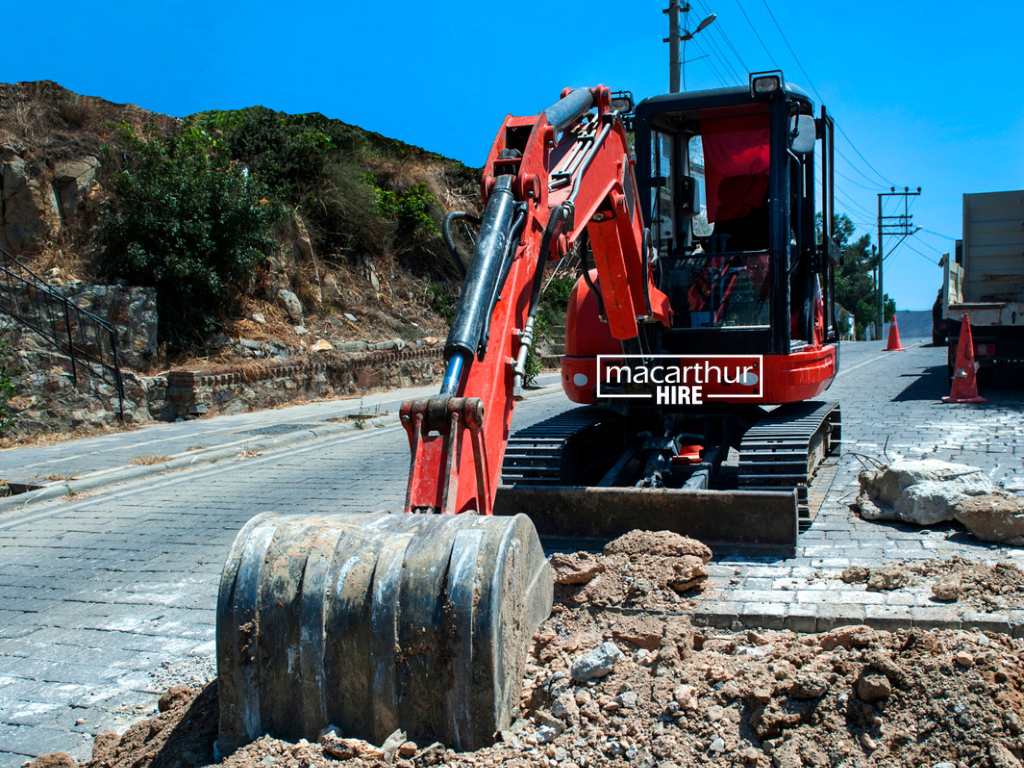 Construction contractor inspecting a compact excavator and reviewing equipment details before arranging machinery hire.